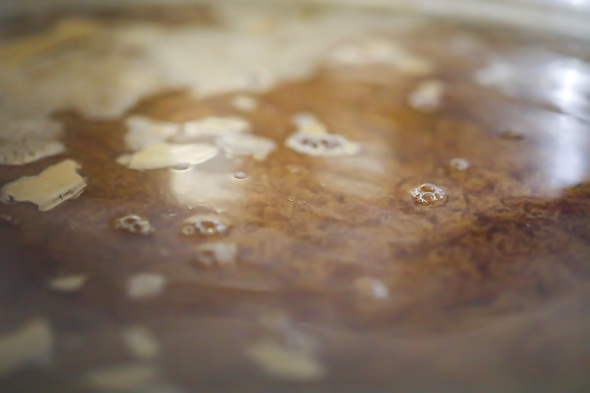 Surface du moût ambré pendant le brassage, avec un peu de mousse.